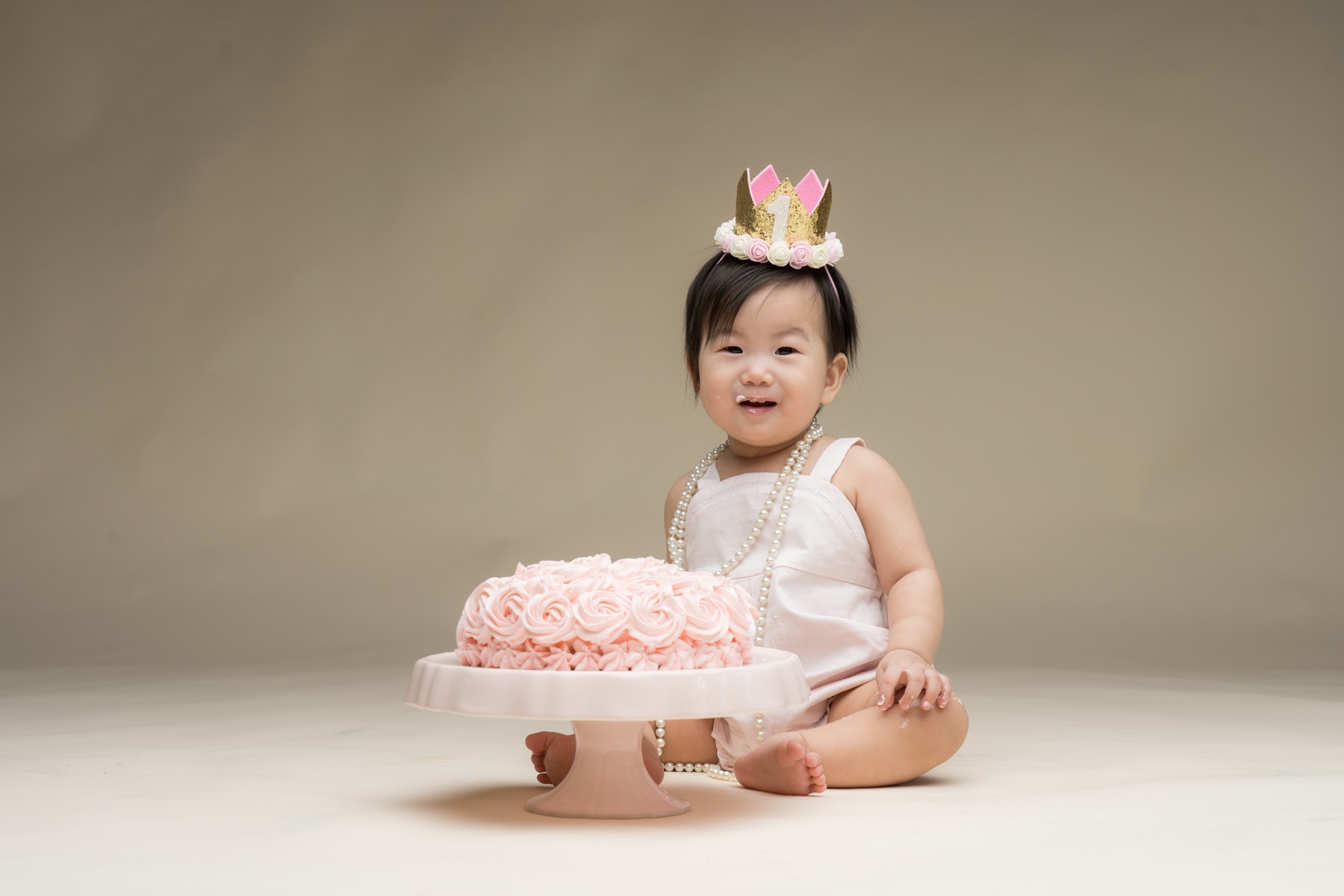 One-year-old child beside a pink birthday cake