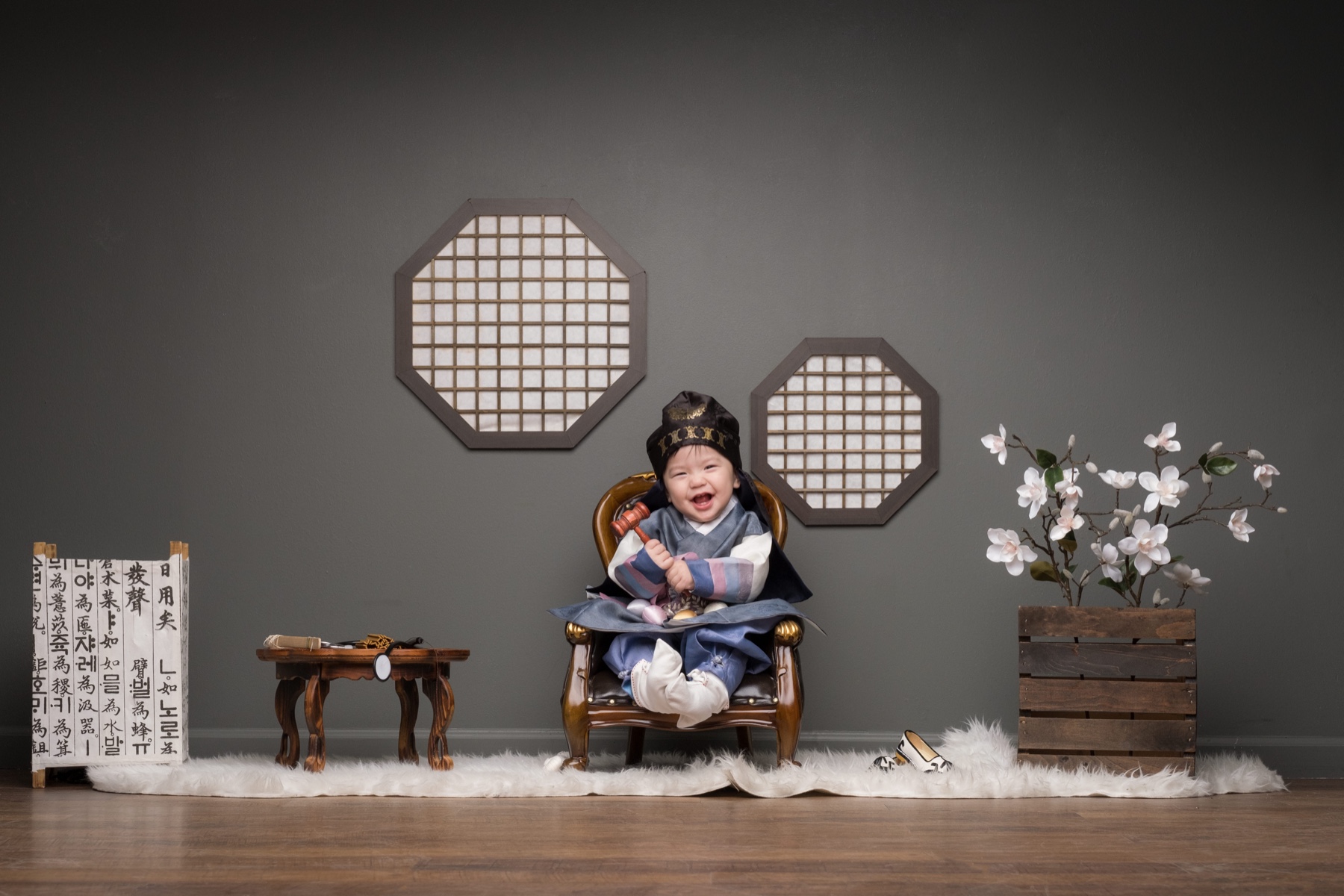 Child in hanbok seated for a Korean first-birthday portrait