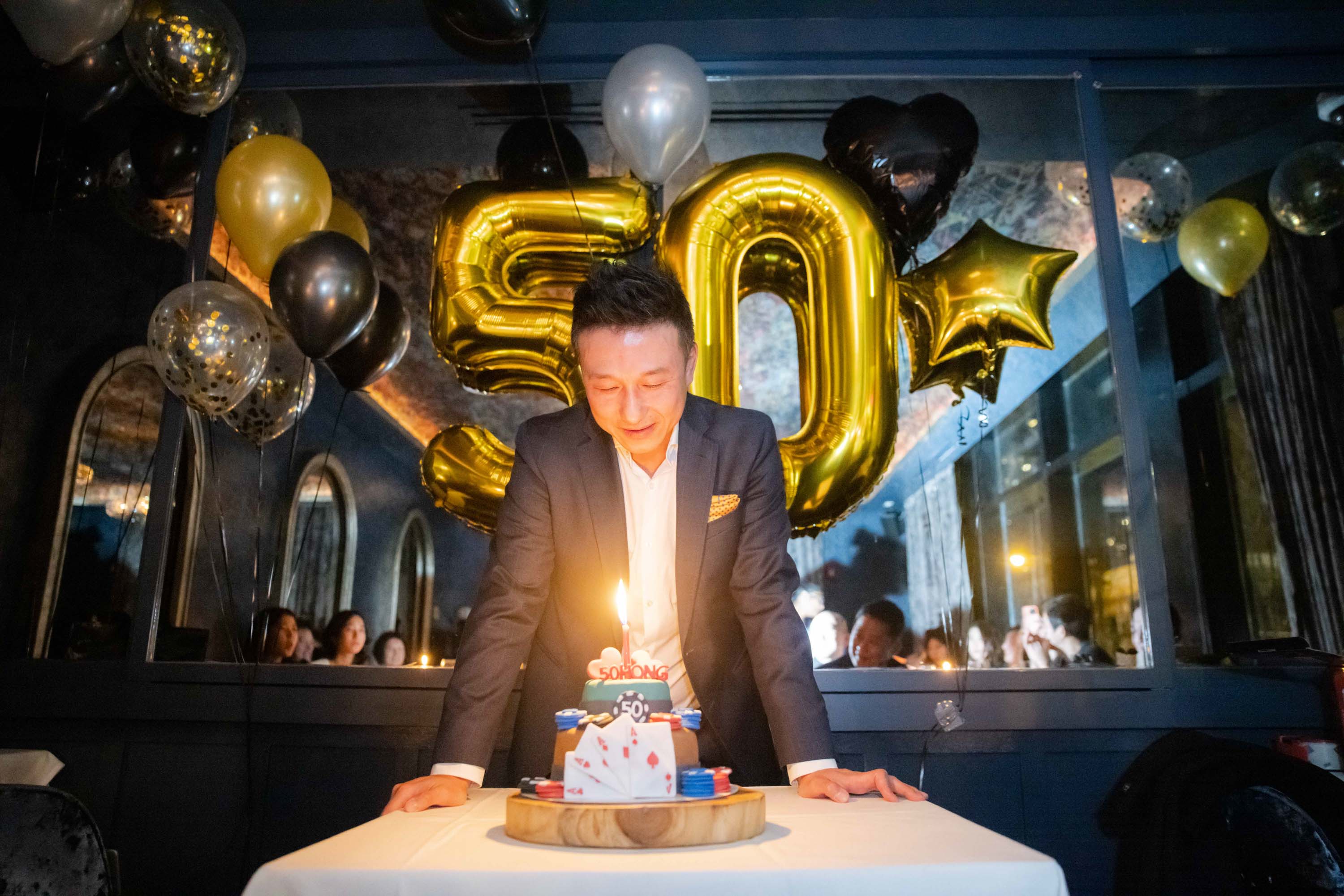 Man leaning over a birthday cake at his fiftieth celebration