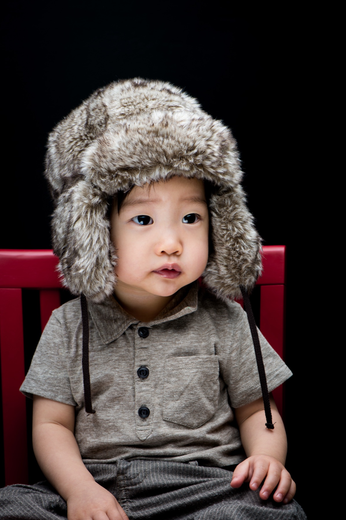 One of Soohyun Kim's sons wearing a fur hat against a dark studio background