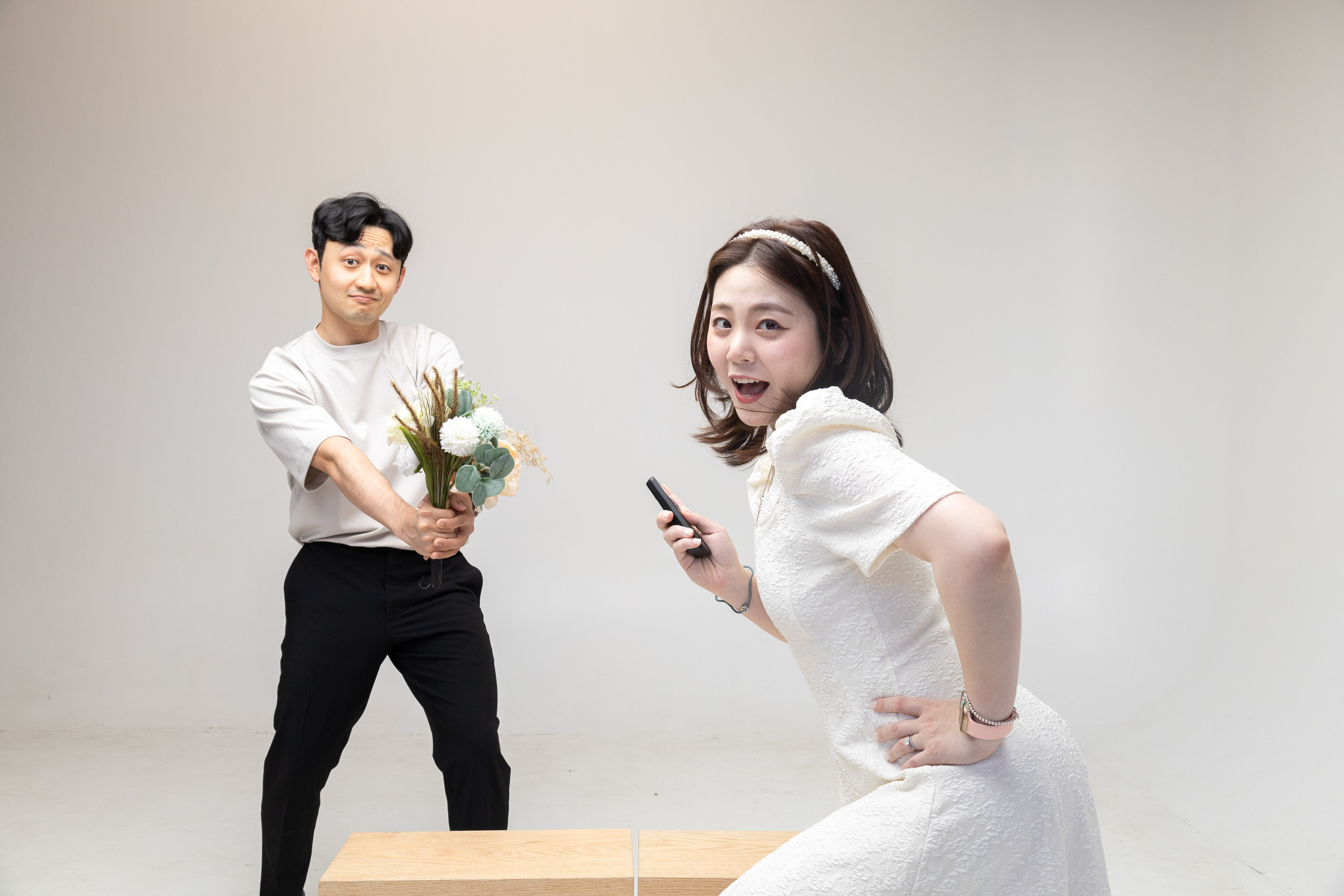 Woman holding a remote shutter with her partner behind her in the studio