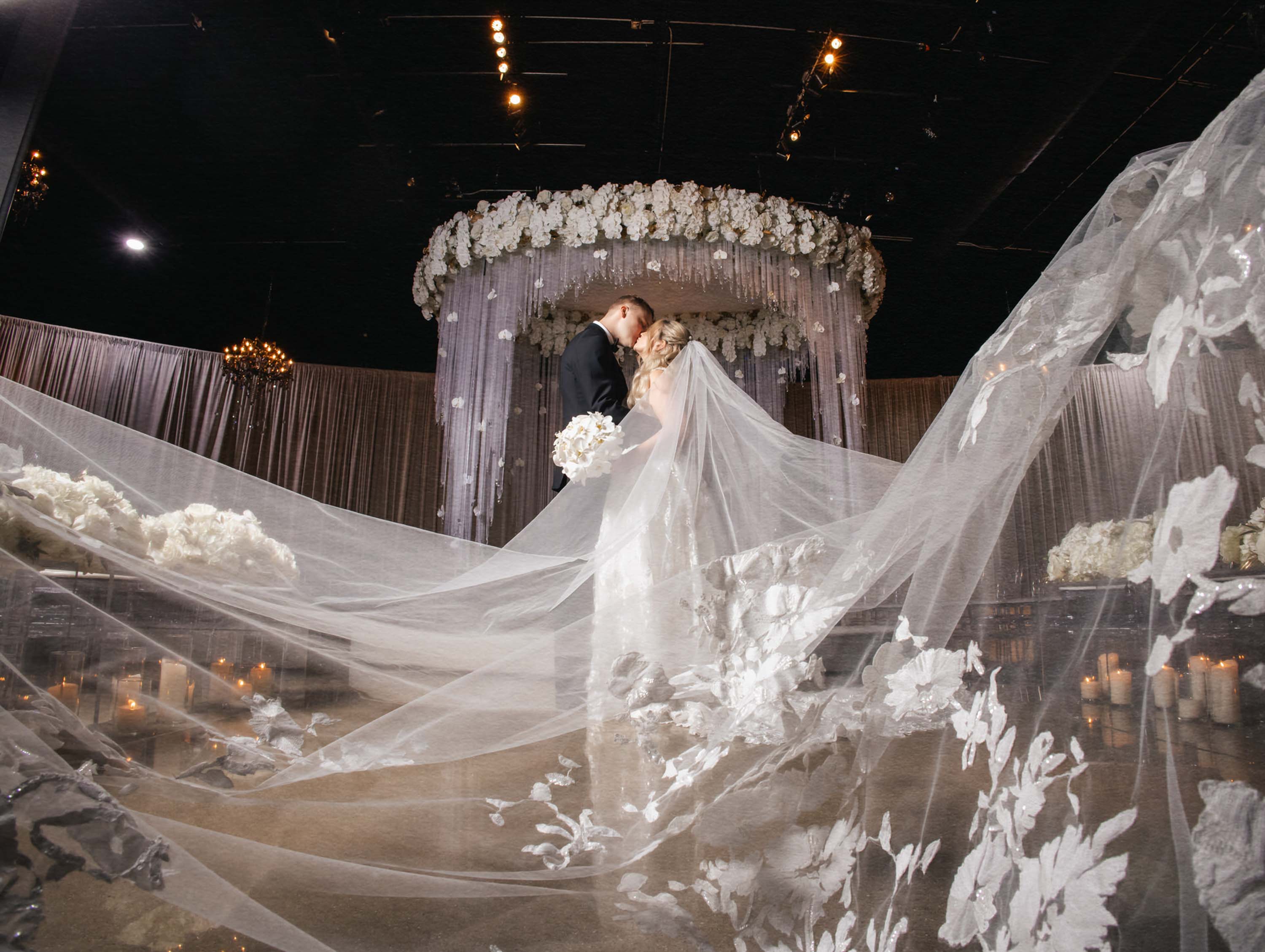 Newlyweds kissing beneath a flowing veil